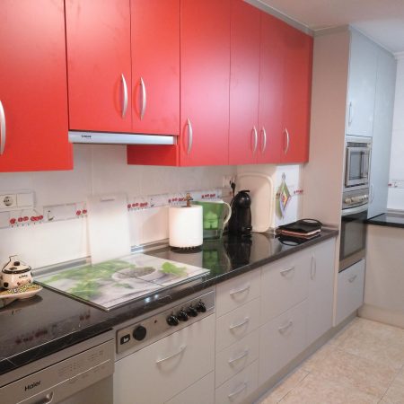 Cocina con puerta en laminado rojo y gris suave. Encimera de aglomerado